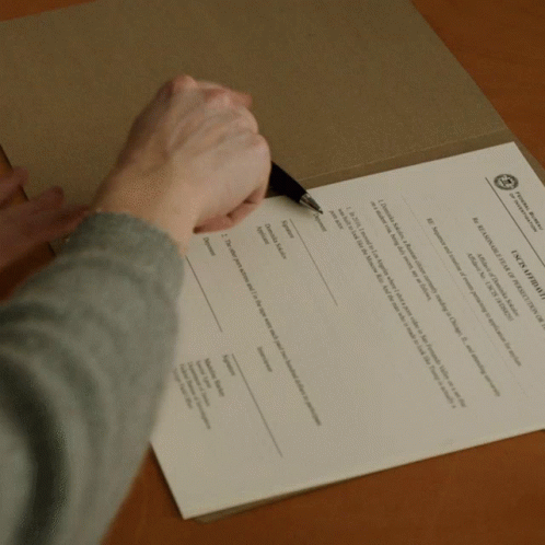 A Person Is Writing On A Piece Of Paper That Says " A Declaration Of Independence " On It GIF