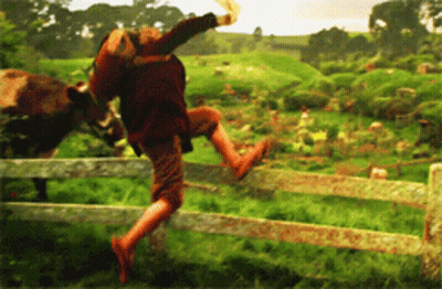 A Person Jumping Over A Wooden Fence With A Cow In The Background GIF