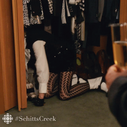 A Person Kneeling In A Closet With A #Schitts Creek Logo On The Bottom GIF