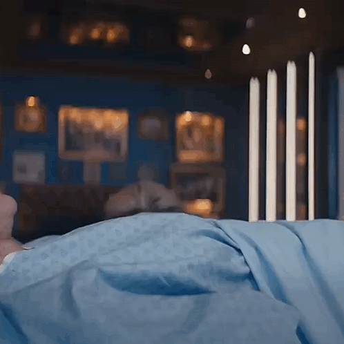 A Person Laying In Bed With A Blue Blanket GIF