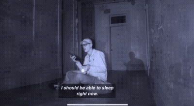 A Person Laying In Sarah 'S Bed With A Flashlight In Their Hand GIF