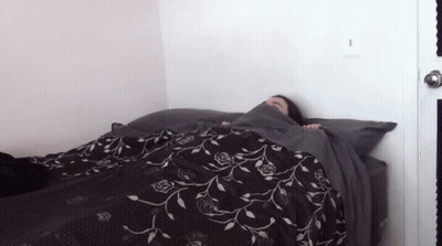 A Person Laying On A Bed With A Black And White Floral Blanket GIF