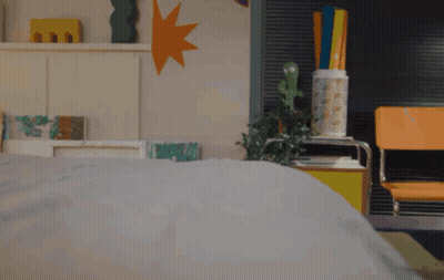 A Person Laying On A Bed With A Cactus On A Table GIF
