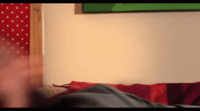A Person Laying On A Bed With A Red And Purple Striped Blanket GIF