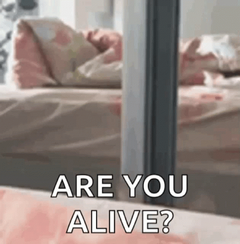 A Person Laying On A Bed With The Words `` Are You Alive '' Written On It . GIF