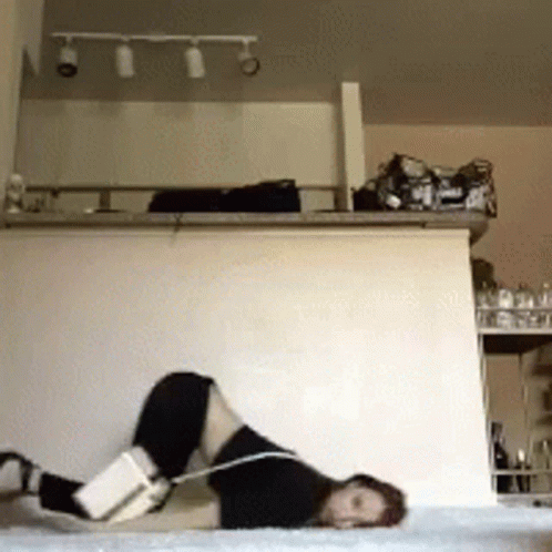 A Person Laying On Their Stomach With A Book On Their Knee GIF