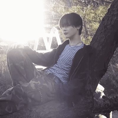 A Person Leaning Against A Tree With The Letter V Visible Behind Them GIF