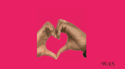 A Person Making A Heart With Their Hands On A Pink Background GIF