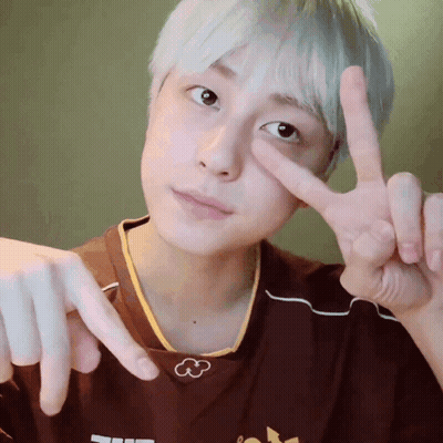 A Person Making A Peace Sign With Their Fingers In Front Of Their Face GIF