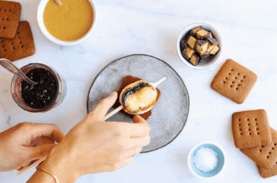 A Person Making A S'mores Sandwich With A Stick GIF