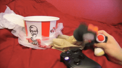 A Person Playing A Video Game Next To A Kfc Cup GIF