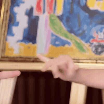 A Person Pointing At A Colorful Painting With A Red Car In The Background GIF