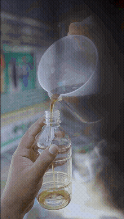 A Person Pouring Liquid Into A Plastic Bottle With A Funnel GIF