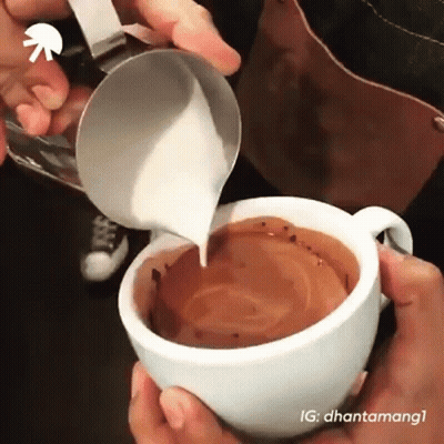 A Person Pouring Milk Into A Cup Of Coffee . GIF