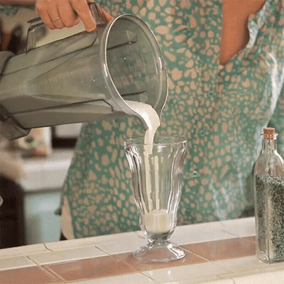 A Person Pouring Milk Into A Glass On A Counter GIF