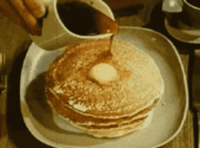 A Person Pouring Syrup On A Stack Of Pancakes GIF