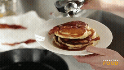 A Person Pouring Syrup On A Stack Of Pancakes With Everyday Food Written On The Bottom GIF