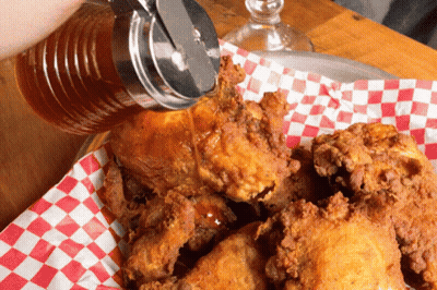 A Person Pouring Syrup Over Fried Chicken On A Checkered Napkin GIF
