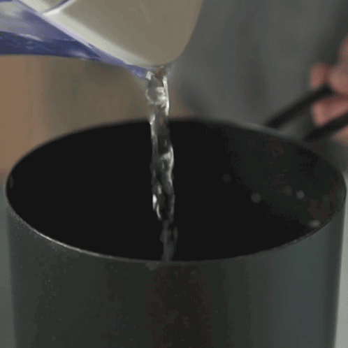 A Person Pouring Water Into A Black Pot With Chopsticks GIF