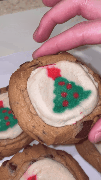 A Person Reaches For A Cookie With A Christmas Tree On It GIF