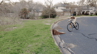 A Person Riding A Bike Down A Road With A Ramp GIF