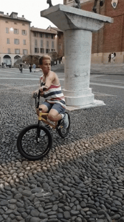 A Person Riding A Bike On A Cobblestone Street GIF