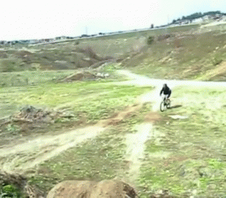 A Person Riding A Bike On A Dirt Road GIF