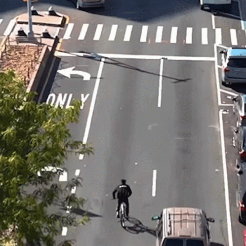 A Person Riding A Bike On A Street With A Sign That Says Only On It GIF