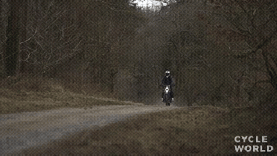 A Person Riding A Motorcycle On A Dirt Road With The Words Cycle World Visible GIF