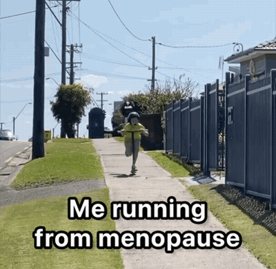 A Person Riding A Scooter Down A Sidewalk With The Words Me Running From Menopause GIF