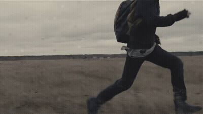 A Person Running In A Field With A Backpack On Their Back GIF