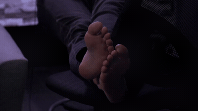 A Person 'S Feet Are Laying On A Chair In A Dark Room GIF