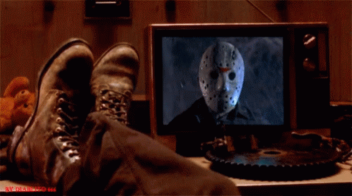 A Person 'S Feet Are Laying On A Table In Front Of A Tv Screen With Jason Voorhees On It GIF