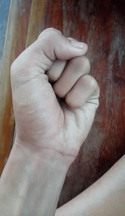 A Person 'S Fist Is Against A Wooden Table GIF