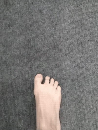 A Person 'S Foot Is Standing On A Gray Carpet . GIF