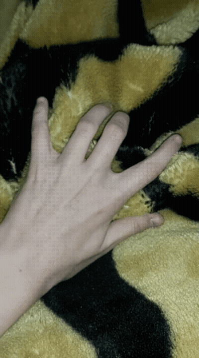 A Person 'S Hand Is Laying On A Black And Yellow Blanket GIF