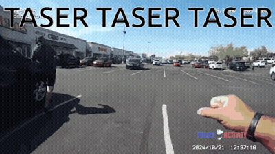 A Person 'S Hand Is Pointing At A Car In A Parking Lot With The Words Taser Taser Taser GIF