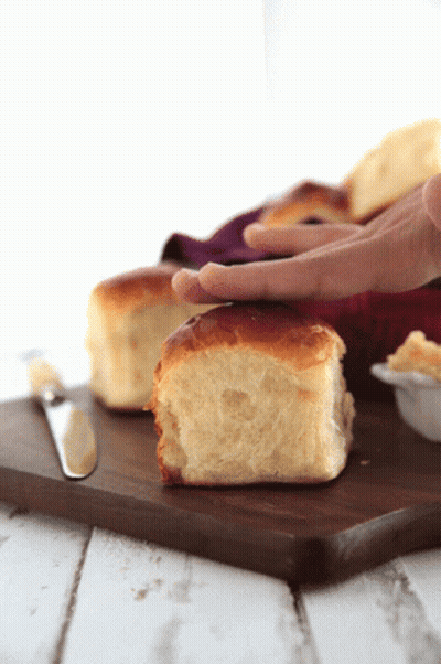 A Person 'S Hand Is Reaching For A Piece Of Bread On A Cutting Board GIF