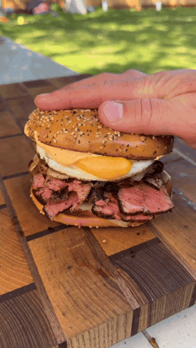 A Person 'S Hand Is Reaching For A Sandwich On A Cutting Board GIF