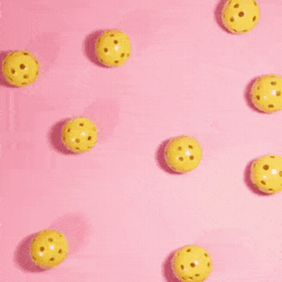 A Person 'S Hand Is Reaching For A Yellow Ball On A Pink Background . GIF