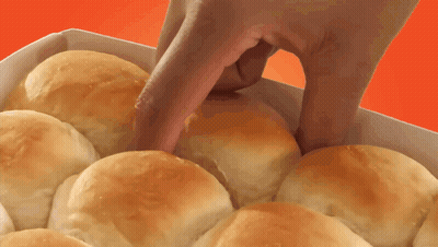 A Person 'S Hand Is Reaching Into A Box Of Rolls GIF