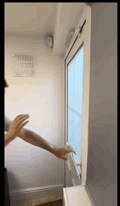 A Person 'S Hand Is Reaching Out To Open A Window GIF