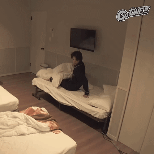 A Person Sits On A Bed In A Room With The Words Go One Written On The Wall GIF