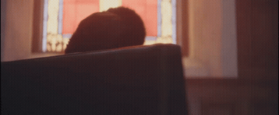 A Person Sitting In A Church Looking Out A Window GIF