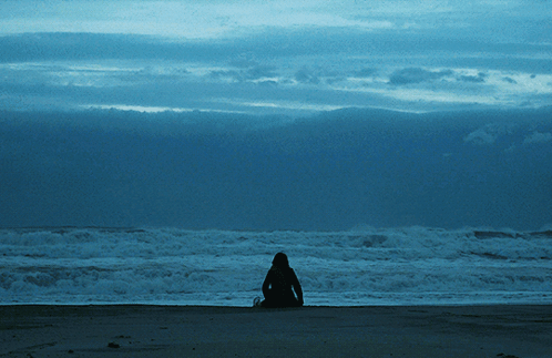 Person Sitting On Beach Looking At Ocean GIF