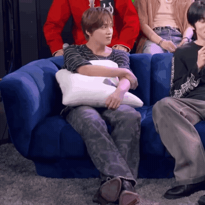 A Person Sitting On A Blue Couch With A Pillow On Their Lap GIF