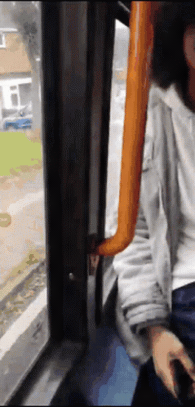 A Person Sitting On A Bus Looking Out Of A Window GIF