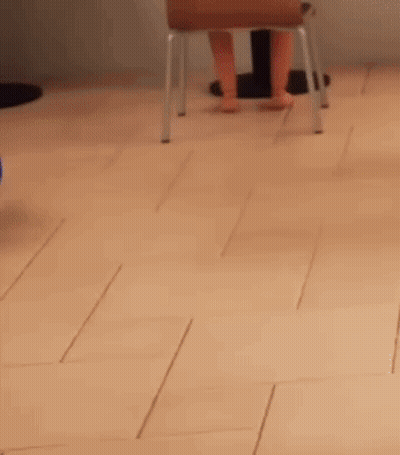 A Person Sitting On A Stool On A Tiled Floor GIF
