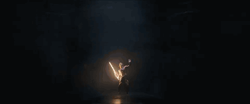 A Person Standing In A Dark Room With A Light Coming Out Of Their Hands GIF