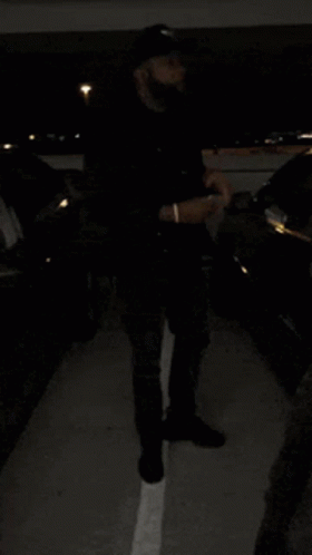 A Person Standing In A Parking Lot With Cars Parked In The Background GIF